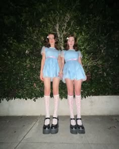 two young women dressed in short blue dresses and white socks standing next to each other