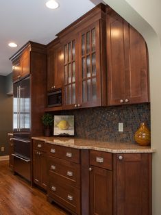 a kitchen with wooden cabinets and granite counter tops, along with hardwood flooring that matches the walls