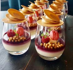 desserts are arranged in glass containers on a table