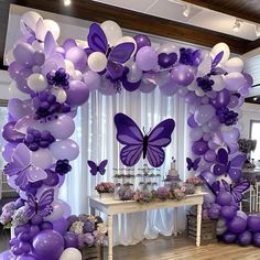 a purple and white balloon arch decorated with butterflies