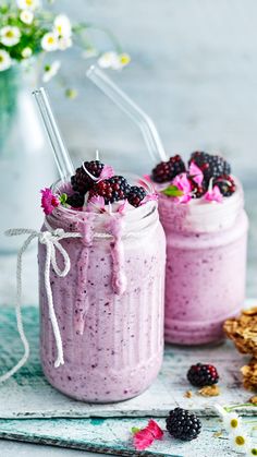 two mason jars filled with berry chia pudding and topped with blackberries, raspberries, and flowers