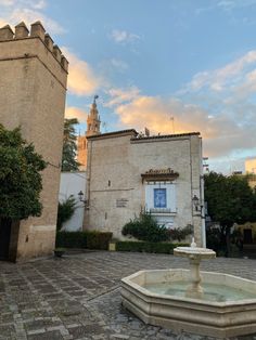 an old building with a fountain in front of it on a cobblestone street