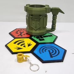 a green coffee mug sitting on top of a table next to four different colored coasters