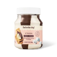 a jar of sweet spread with chocolate and marshmallows on the side, in front of a white background