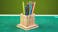 a pencil holder made out of popsicle sticks on a cutting board with green background