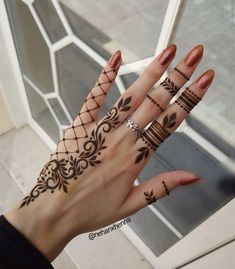 a woman's hand with hennap tattoos on her fingers and wrist,