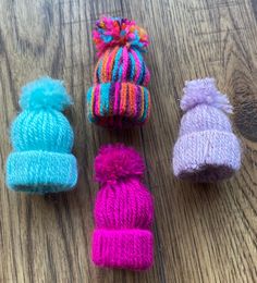 three knitted hats and one crochet hat on a wooden surface