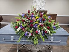 a blue casket with flowers and greenery on it in a church lobby or waiting room