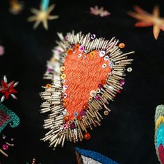 an embroidered heart surrounded by pins and needles on a black surface with stars in the background