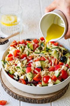 someone pouring dressing into a bowl full of salad