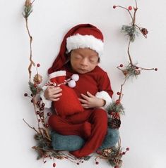 a baby wearing a santa hat and holding a teddy bear