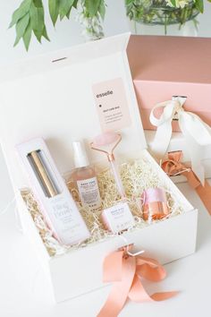 a white box with pink ribbon and some bottles in it