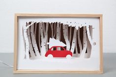 a red car driving through a forest filled with trees and white snow on the ground