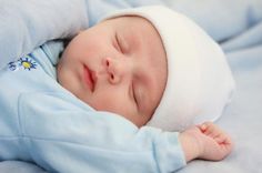 a sleeping baby with a blue blanket and white headband on it's face