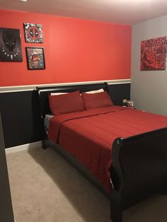 a bed with red sheets and pillows in a room that has two pictures on the wall