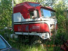 an old red and white truck parked in the woods