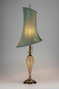 a table lamp with a green shade on the bottom and gold trim around the base