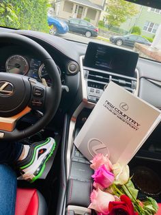 the interior of a car with flowers, books and other items in front of it