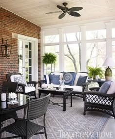 a living room filled with lots of furniture next to a brick wall and ceiling fan