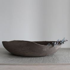 a wooden bowl sitting on top of a white counter next to a planter filled with flowers