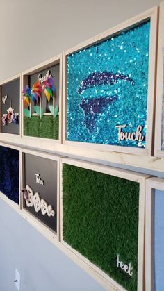 there are many pictures on the wall with fake grass in each frame and words below them