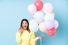 a woman is holding balloons and posing for the camera with her hands in front of her face