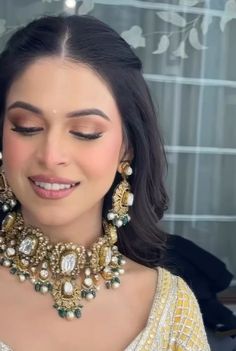 a woman wearing an elaborate necklace and earrings with pearls on her neck, smiling at the camera