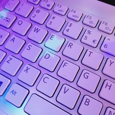 a close up view of a keyboard with purple lighting on the top and bottom keys