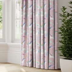 pink curtains with unicorns and rainbows printed on them in front of a window