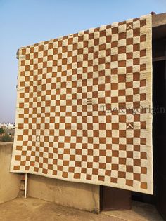 a large brown and white checkered blanket on the side of a building