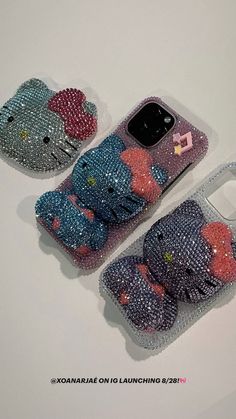 three cell phones with hello kitty cases on them sitting next to each other in front of a white background