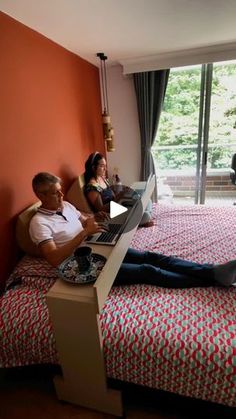 two people sitting on a bed using laptops