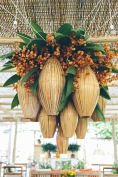 an arrangement of flowers hanging from the ceiling in a room with wicker chairs and tables