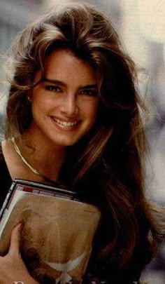 a woman holding a book and smiling at the camera