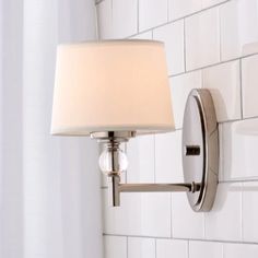 a wall light with a white fabric shade on it's arm and the bulb turned off