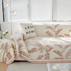 a living room with a white couch covered in a love home blanket next to a coffee table