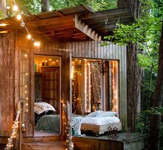 a small wooden cabin with lights hanging from the ceiling and bed in it's corner