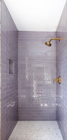 a walk in shower sitting next to a tiled wall and floor covered in purple tiles