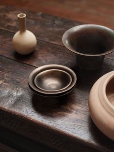 three bowls and one vase on a wooden table