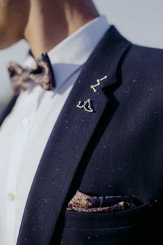 a man wearing a suit and tie with small bow ties on his lapel collar