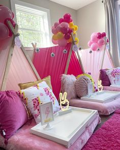 a room with pink and yellow decor on the walls, pillows and balloons in the ceiling