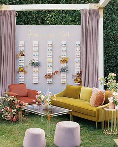 a living room filled with furniture and flowers on the wall next to a window covered in pink drapes