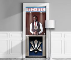 a man in a vest and tie holding a trophy standing next to a ticket booth