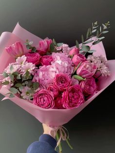 a person holding a bouquet of pink flowers