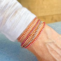 a woman's arm with four different colored bracelets on top of each other