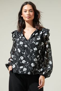 We're absolutely feeling a type of way about all the cute details on the Marilu Floral Ruffle Top. This blouse features divine ruffle details on the shoulders followed by long sheer sleeves with an elastic stretch on the cuffs. A relaxed body it fitted perfectly in this top. Whether you're going for a bohemian-inspired look or aiming for a soft and dreamy style, this blouse will effortlessly elevate your outfit.- Ruffle details- Split neck- Lined- Balloon sleeves- Color: Black whiteSize + Fit - Spring Night Out Blouse With Ruffle Hem, Spring Ruffle Hem Blouse For Night Out, Elegant Ruffle Sleeve Blouse With Floral Print, Elegant Ruffle Sleeve Floral Print Blouse, Elegant Blouse With Floral Print And Ruffle Sleeves, Sheer Tops With Ruffled Collar, Spring Black Blouse With Smocked Cuffs, Spring Ruffle Sleeve Blouse For Night Out, Elegant Tops With Smocked Cuffs And Ruffle Sleeves