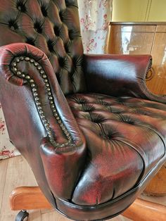 a brown leather chair sitting on top of a wooden floor