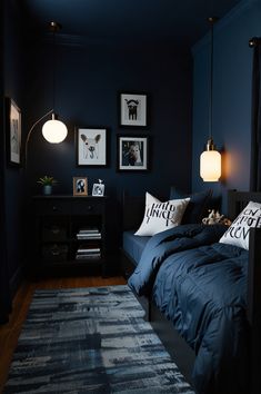 a bedroom with dark blue walls and pictures on the wall, along with an area rug