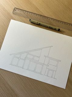 a piece of paper with a drawing of a house on it next to a ruler