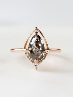 an engagement ring with a pear shaped gray diamond in the center and two diamonds on each side